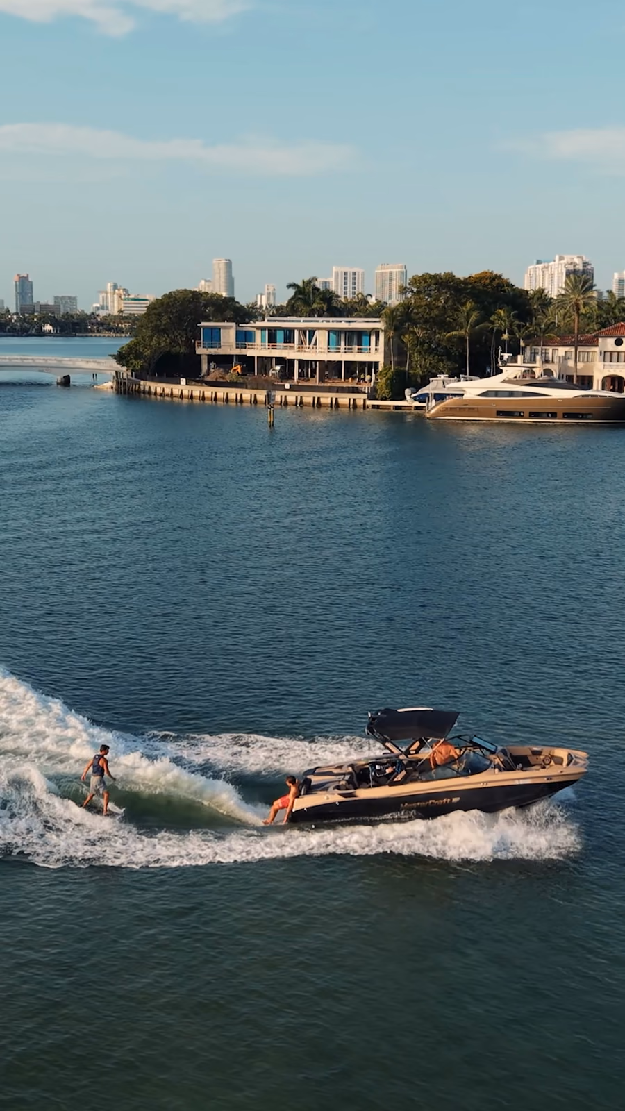 Drone view of the wake boat and a rider carving the wake on Biscayne Bay, Miami skyline behind
