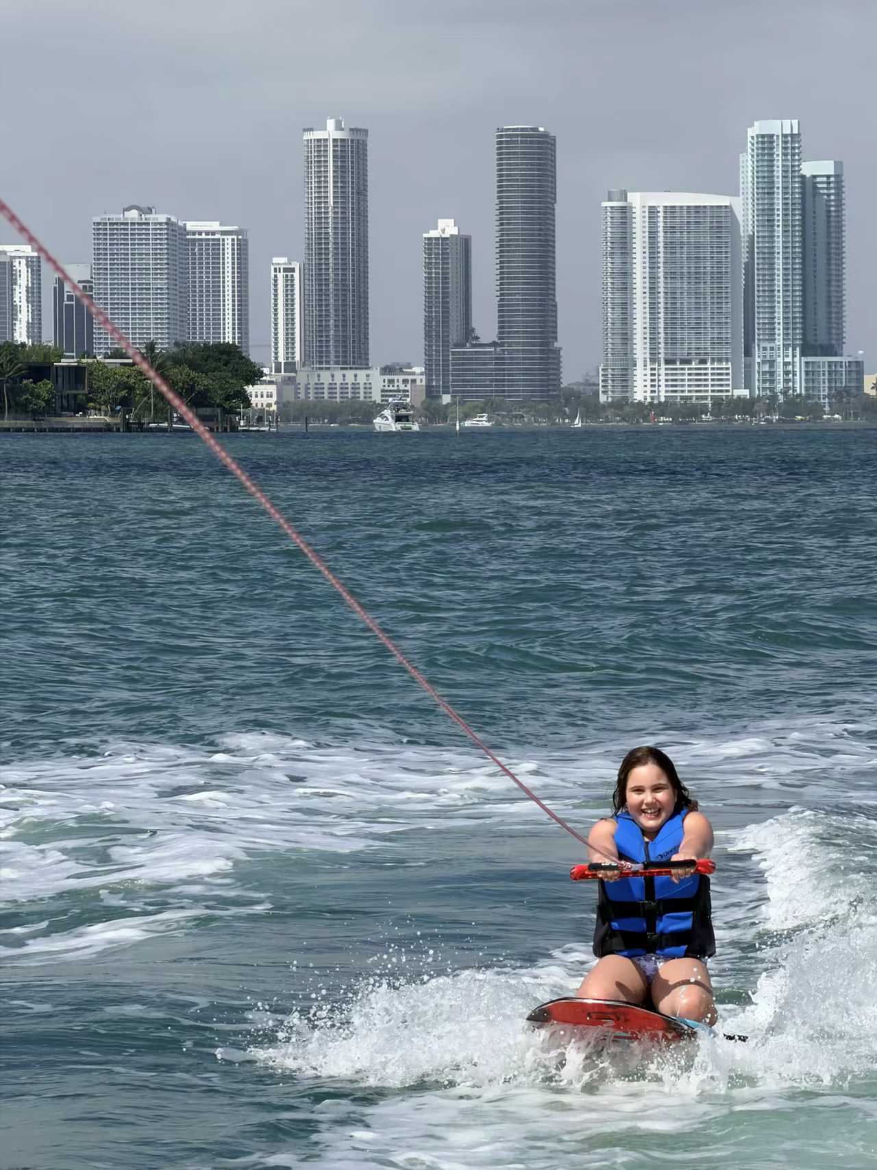 Una niña montando detrás del barco en la Bahía de Biscayne, con el skyline de Miami al fondo