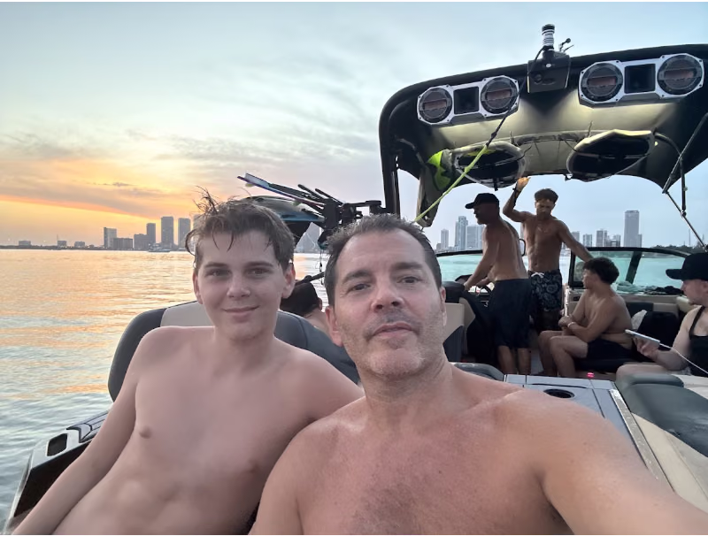 Matthieu's own photo: sunset selfie with his son on the boat, Miami skyline behind